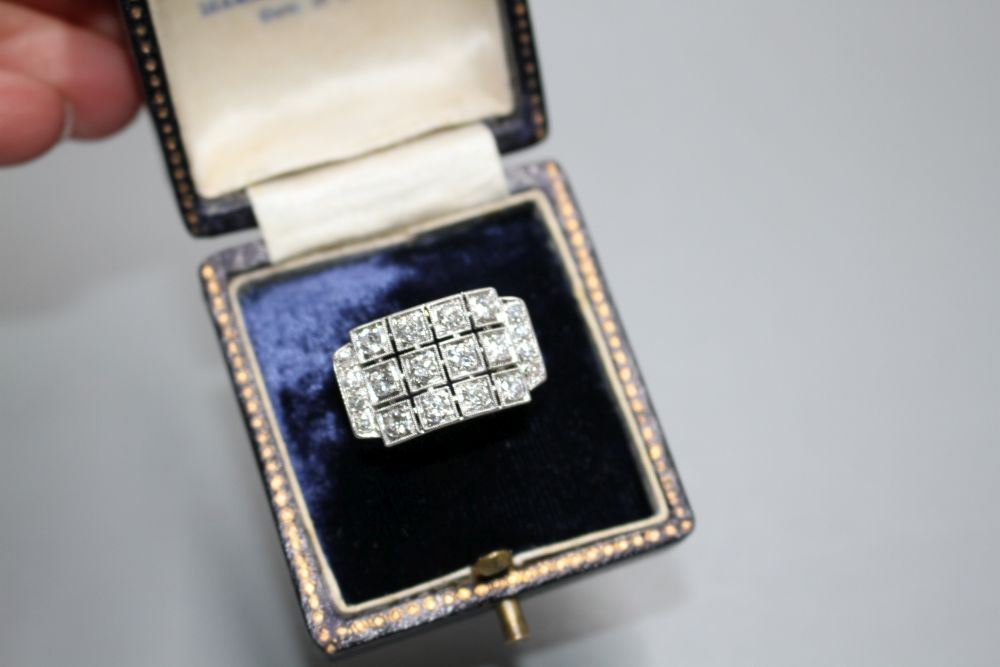 A white metal (stamped 750 and Pt 950) and pave diamond set cocktail ring, of curved design and set with twenty round cut stones.